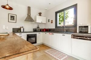 a kitchen with white cabinets and a large window at La Verdière - Contemporary house with garden and private pool in LʼIsle-sur-la-Sorgue