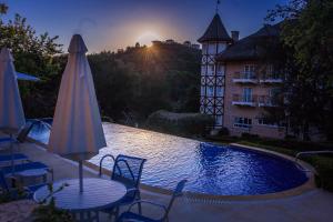 a pool with chairs and an umbrella and a building at Carballo Hotel & Spa in Campos do Jordão
