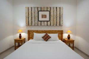沙努尔Bali Komang Guest House Sanur的卧室里有一张白色的大床，床边还有两盏灯