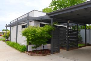 a black and white house with a tree in front of it at 16 King Street in Myrtleford