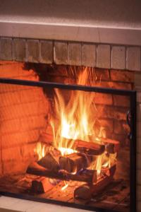 a fire burns in a brick fireplace at Carballo Hotel & Spa in Campos do Jordão