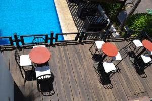 um deque com mesas e cadeiras junto a uma piscina em Landmark Suites em Los Mochis