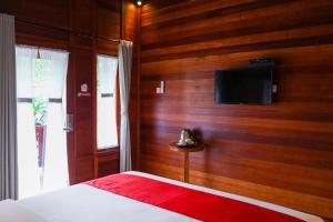 1 dormitorio con pared de madera y TV. en La'villaris hotel & resto en Kuta Lombok