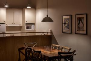 a kitchen with a wooden table with chairs and a kitchen counter at Squatters Run Apartments in Thredbo