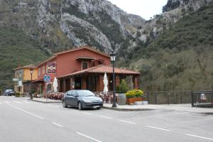 un coche aparcado frente a un edificio con una montaña en Hostal Monte Rio, en Peñamellera Alta