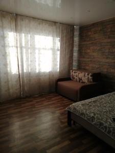 ein Schlafzimmer mit einem Bett, einem Fenster und einem Sofa in der Unterkunft Apartment Комфорт для Вас in Krasnojarsk