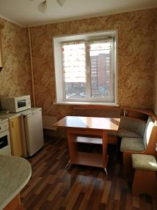 eine Küche mit einem Holztisch und einem Fenster in der Unterkunft Apartment Комфорт для Вас in Krasnojarsk