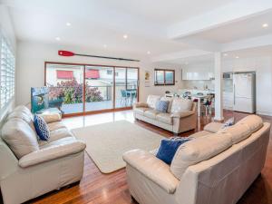 ein Wohnzimmer mit 2 Sofas und einer Küche in der Unterkunft Seagrass House in Yamba