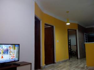 uma sala de estar com paredes amarelas e uma televisão de ecrã plano em Temporada Casa dos sonhos Peruíbe em São Paulo