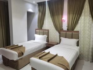 two beds in a hotel room with curtains at Ostrava Suites in Abha