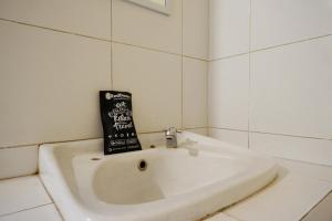 a white sink in a white tiled bathroom at RedDoorz @ Hotel Citra Indah in Yogyakarta