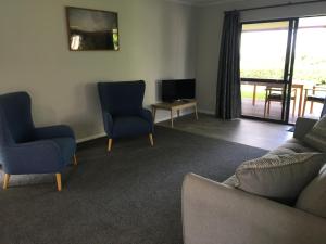 a living room with a couch and chairs and a television at Te Harinui - Peaceful rural escape in Tauranga