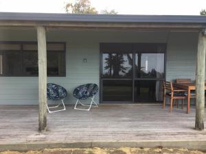 two chairs sitting on the porch of a house at Te Harinui - Peaceful rural escape in Tauranga