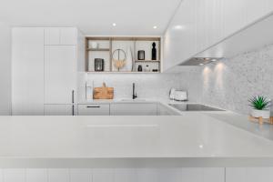 a white kitchen with white cabinets and a sink at Oceanbreeze - Sunshine Beach Ocean Views in Sunshine Beach