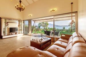 a living room with a couch and a large window at Luna Villa by StayVista - Lakeside charm with Terrace, Lush lawn & Modern decor in Nashik