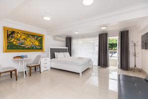 a white bedroom with a bed and a table at Homestay coco in Vung Tau