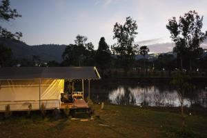 een tent in een veld naast een meer bij Thara Hidden Camp in Khao Kho