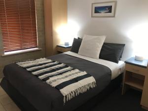 a bedroom with a bed with a striped blanket on it at Esperance Central Accommodation in Esperance