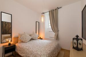 a bedroom with a white bed and two windows at LE GRIFFON in Colmar