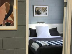 
a bedroom with a bed, mirror and a painting on the wall at Esperance Central Accommodation in Esperance
