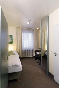 a hotel room with a bed and a window at Hotel Monopol City Centre in Düsseldorf