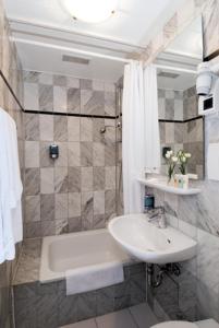 a bathroom with a sink and a tub and a toilet at Hotel Monopol City Centre in Düsseldorf