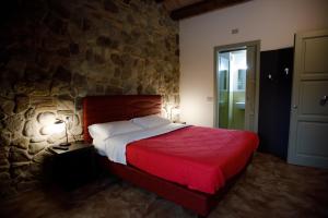 una camera con un letto rosso e una parete in pietra di Modus Aquae a Brisighella