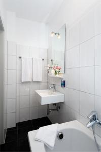 a white bathroom with a sink and a mirror at Hotel Monopol City Centre in Düsseldorf