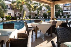加藤達拉特索的住宿－Okeanis Golden Resort，游泳池旁的餐厅配有桌椅