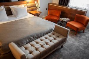 a bedroom with a bed with a couch and two chairs at New City Hotel & Restaurant Niš in Niš