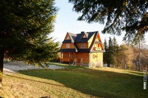 a large wooden house with a gambrel roof at Noclegi u Hanki in Bukowina Tatrzańska