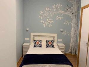 um quarto com uma cama com um mural de árvore na parede em Cumbres de los Picos Apartamento Urriellu em Poo de Cabrales
