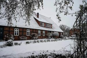 een huis met sneeuw op de grond ervoor bij Hof Lohmann in Verden