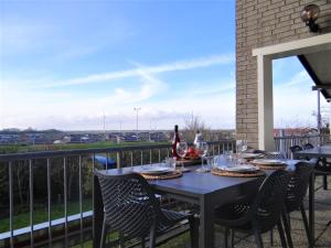 a table with a bottle of wine on a balcony at Familie-Beachvilla Ooster-schel-de in Kamperland