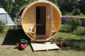 a small wooden sauna in a yard with flowers at Hasle Camping & Hytter in Hasle