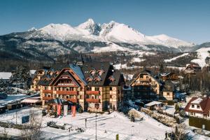 a large building with snow covered mountains in the background at APLEND Hotel Kukučka in Vysoke Tatry - Tatranska Lomnica.