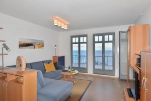 a living room with a blue couch and some windows at Haus am Kliff 08 in Heringsdorf