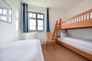 a bedroom with two bunk beds and a chair at Haus am Kliff 08 in Heringsdorf