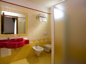 bagno con lavandino, servizi igienici e specchio di Hotel Arena a Rimini