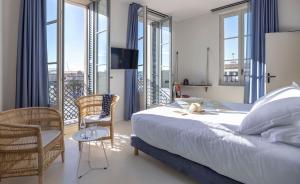 
a room with a bed, chair, desk and a window at L'Eautel Toulon Centre Port in Toulon
