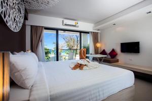 Un dormitorio con una gran cama blanca con una silla. en Coral Inn, en Karon Beach