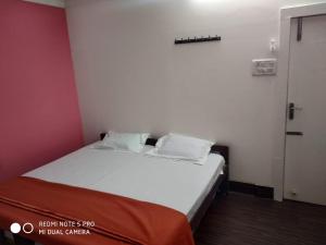 a small bedroom with a white bed and a red wall at The coloursinn Home stays in Chennai