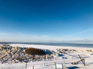 einen Strand mit Schnee auf dem Sand und dem Meer in der Unterkunft Ferienwohnung Nordlicht in Norden