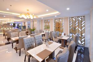 a dining room with tables and chairs and a restaurant at Grand Senyum Hotel, Tugu Yogyakarta in Yogyakarta