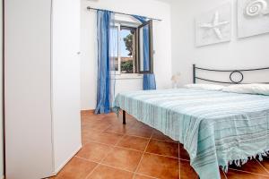 1 dormitorio con 1 cama con cortinas azules y ventana en Trilocale Capo Testa, en Capo Testa