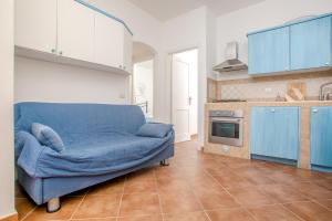 un sofá azul en una cocina con armarios azules en Trilocale Capo Testa, en Capo Testa