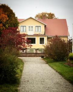 una casa amarilla con techo rojo y entrada de grava en Gamla Gästgivaregården en Södvik