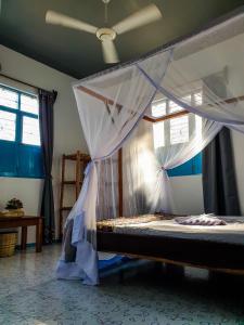 a bedroom with a bed with a mosquito net at Déjà Blue in Paje