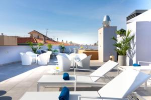 d'une terrasse sur le toit avec des chaises blanches et des tables. dans l'établissement Calafell Home Apartments, à Calafell