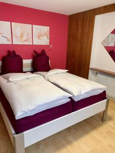 a bedroom with a bed with a pink wall at Bergröschen in Saas-Grund